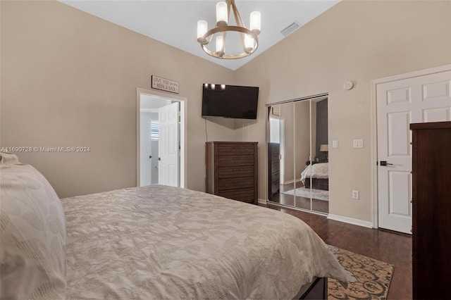 bedroom with dark wood-type flooring, a closet, an inviting chandelier, and lofted ceiling