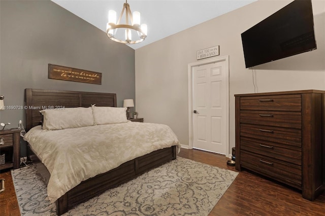 bedroom with dark hardwood / wood-style flooring, lofted ceiling, and a chandelier