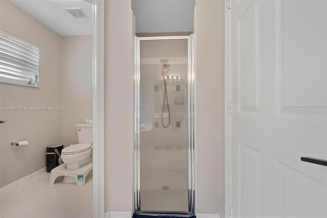 bathroom featuring a shower with shower door and toilet