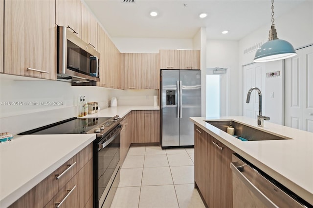 kitchen featuring stainless steel appliances, sink, light brown cabinetry, light tile patterned floors, and decorative light fixtures