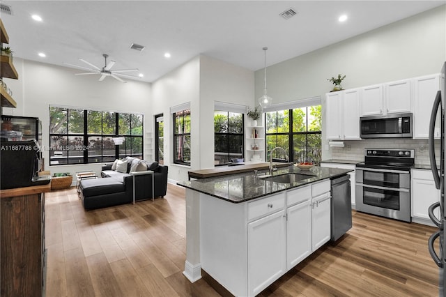 kitchen featuring stainless steel appliances, sink, ceiling fan, an island with sink, and a towering ceiling