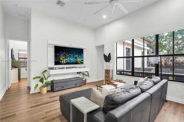 living room featuring a towering ceiling, wood-type flooring, and ceiling fan