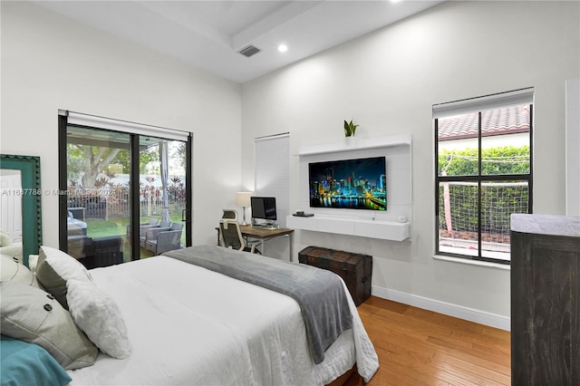 bedroom with access to outside, multiple windows, and light hardwood / wood-style flooring