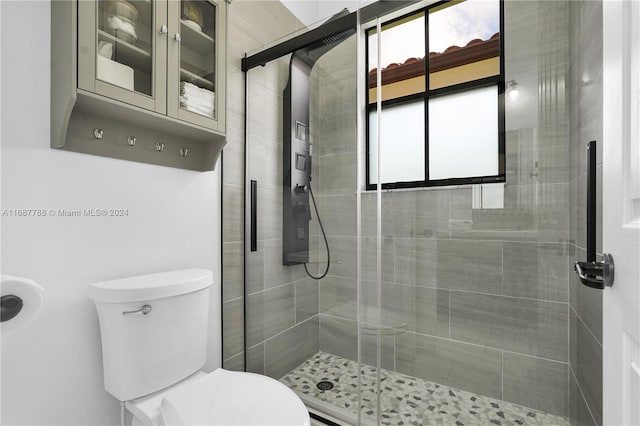 bathroom with a shower with shower door and toilet