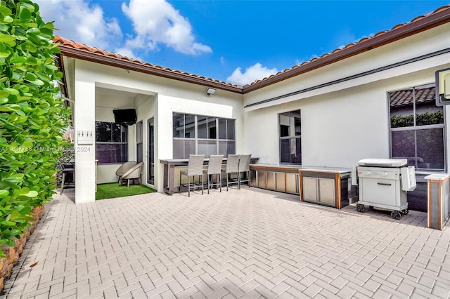 view of patio with exterior bar and a grill