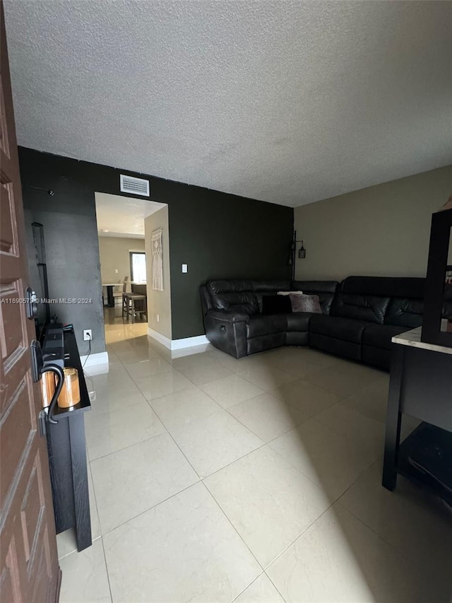 tiled living room featuring a textured ceiling