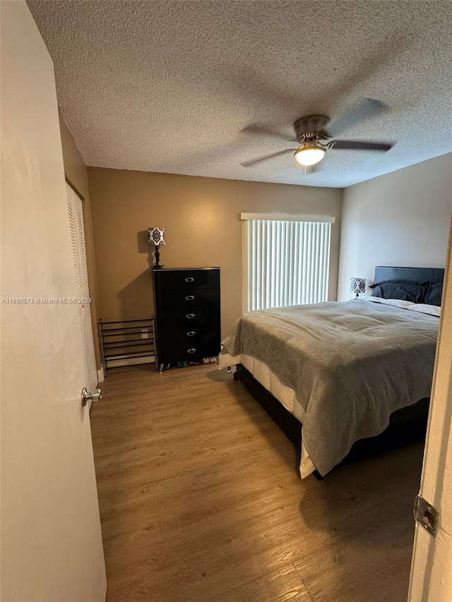 bedroom with light hardwood / wood-style floors, ceiling fan, a textured ceiling, and a closet