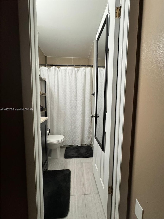 bathroom with toilet, vanity, tile patterned floors, and curtained shower