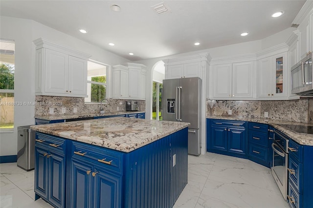 kitchen featuring tasteful backsplash, appliances with stainless steel finishes, white cabinets, blue cabinets, and a center island