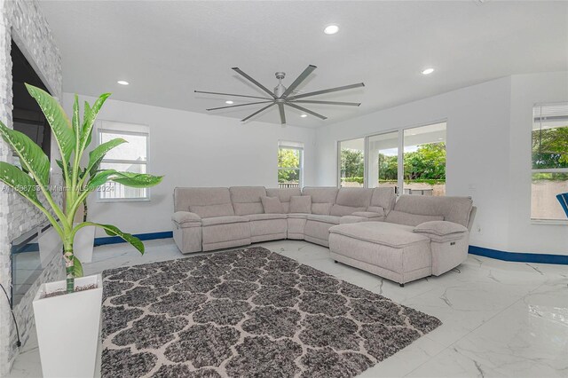 living room with a fireplace, plenty of natural light, and ceiling fan