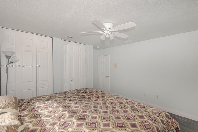 bedroom with a textured ceiling, two closets, and ceiling fan