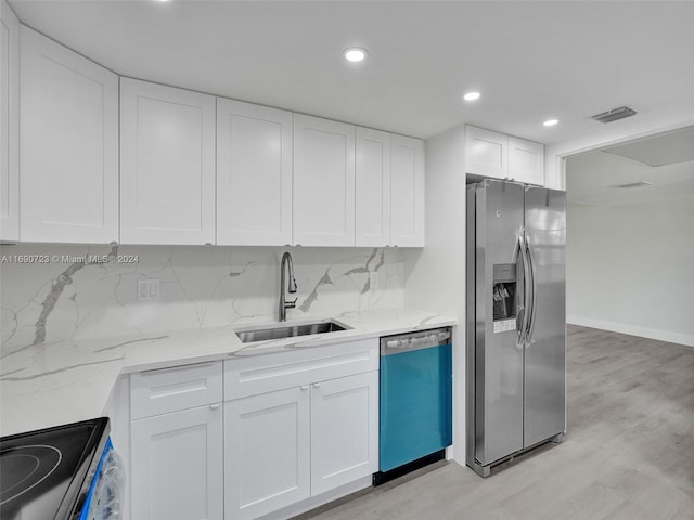 kitchen featuring white cabinetry, appliances with stainless steel finishes, backsplash, and light hardwood / wood-style flooring