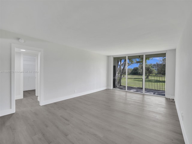 3700 Oaks Clubhouse Dr Unit 203, Pompano Beach, FL 33069 - empty room with wood finished floors, baseboards, expansive windows, and a smoke detector