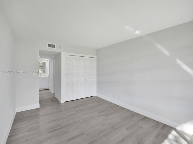 unfurnished bedroom with a closet and light wood-type flooring