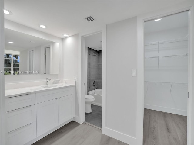 full bathroom featuring hardwood / wood-style floors, vanity, toilet, and tiled shower / bath