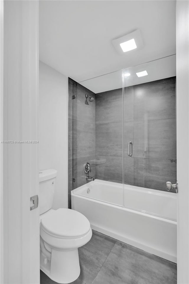 bathroom featuring tile patterned flooring, enclosed tub / shower combo, and toilet