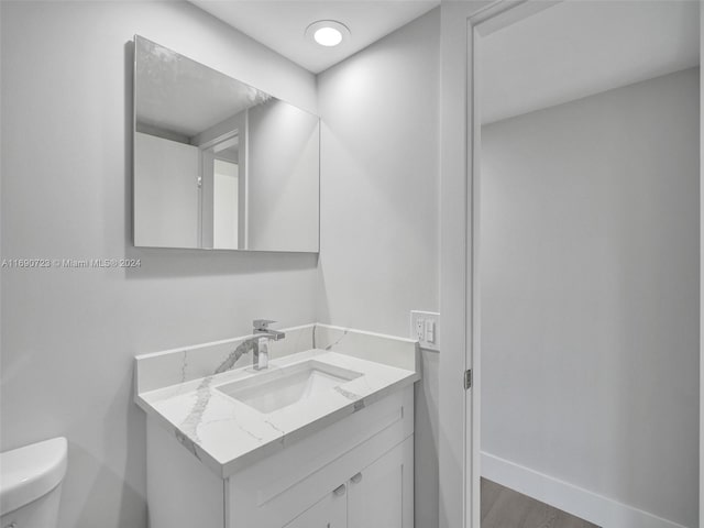 bathroom with wood-type flooring, vanity, and toilet