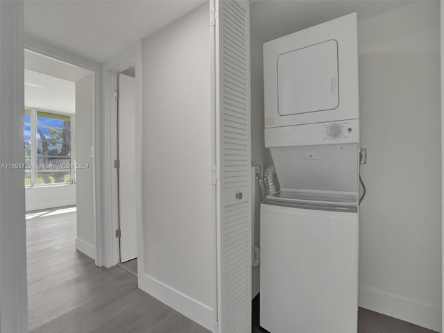 laundry room featuring stacked washer / drying machine and light hardwood / wood-style floors