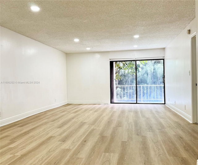 unfurnished room featuring a textured ceiling and light wood-type flooring