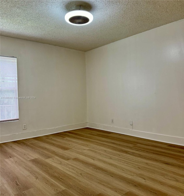 unfurnished room featuring light hardwood / wood-style floors and a textured ceiling