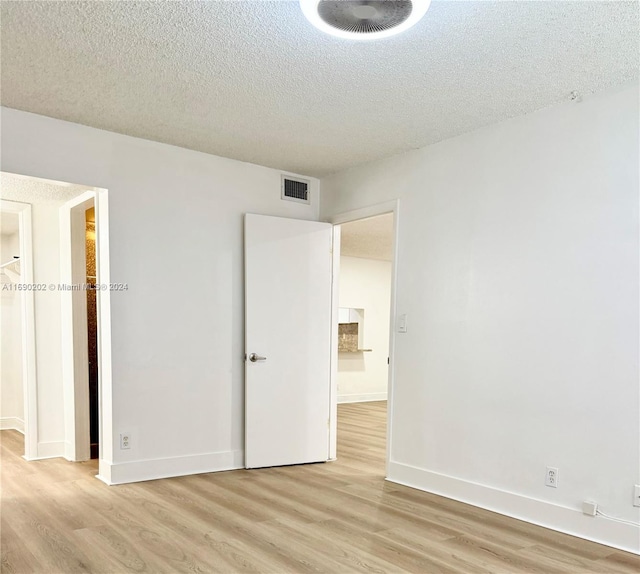 unfurnished bedroom featuring light wood-type flooring and a textured ceiling