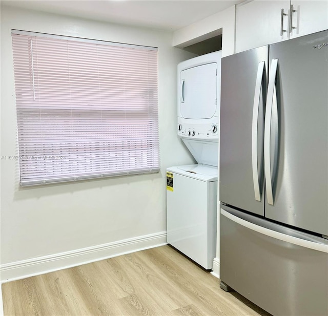 clothes washing area featuring light hardwood / wood-style flooring and stacked washer / drying machine