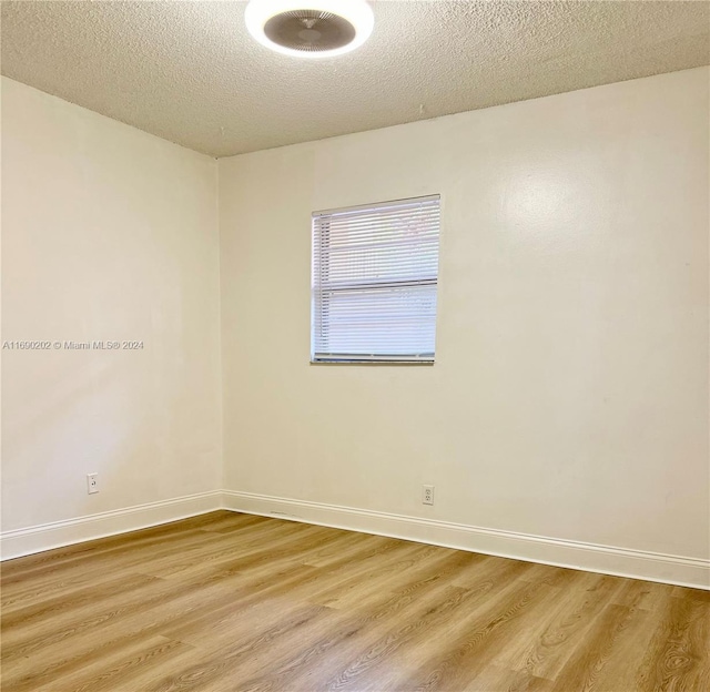 spare room featuring hardwood / wood-style floors and a textured ceiling