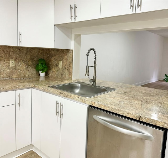 kitchen with hardwood / wood-style floors, stainless steel dishwasher, sink, and white cabinets