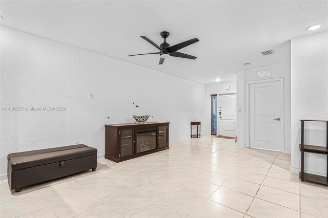 tiled living room featuring ceiling fan and a textured ceiling