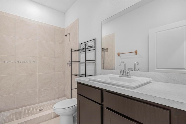 bathroom featuring vanity, toilet, and a tile shower