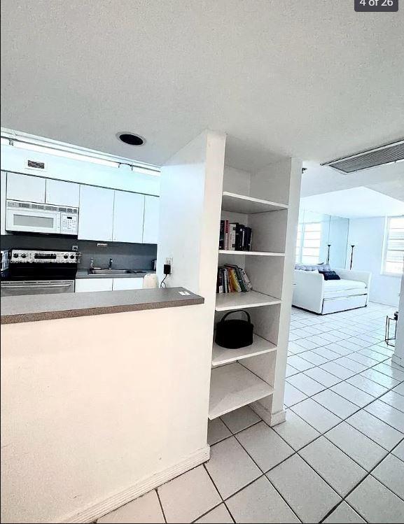 kitchen featuring electric stove, white cabinets, a textured ceiling, sink, and light tile patterned flooring