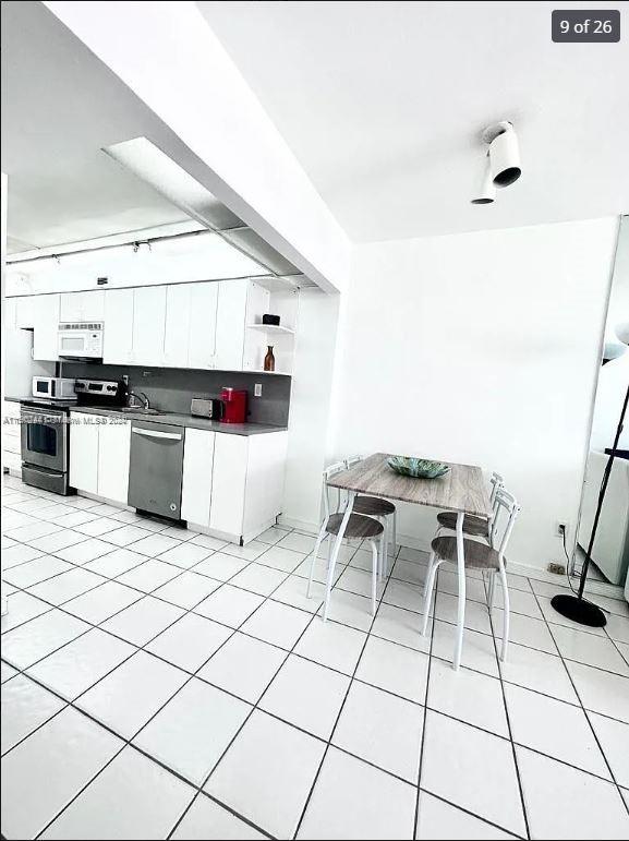 kitchen featuring white cabinets, light tile patterned flooring, and appliances with stainless steel finishes