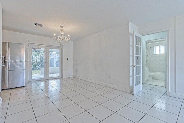 tiled empty room featuring an inviting chandelier and french doors