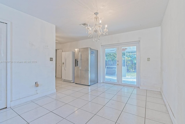 empty room with a notable chandelier and light tile patterned floors