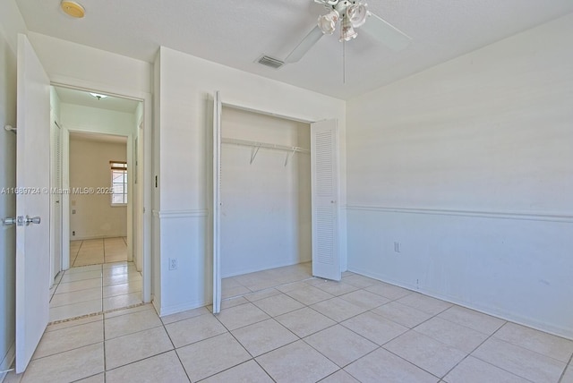 unfurnished bedroom with ceiling fan, light tile patterned flooring, and a closet