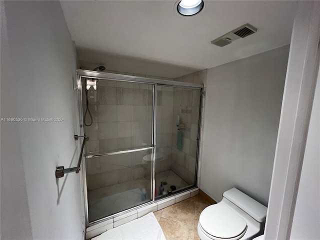 bathroom featuring toilet, an enclosed shower, and tile patterned floors