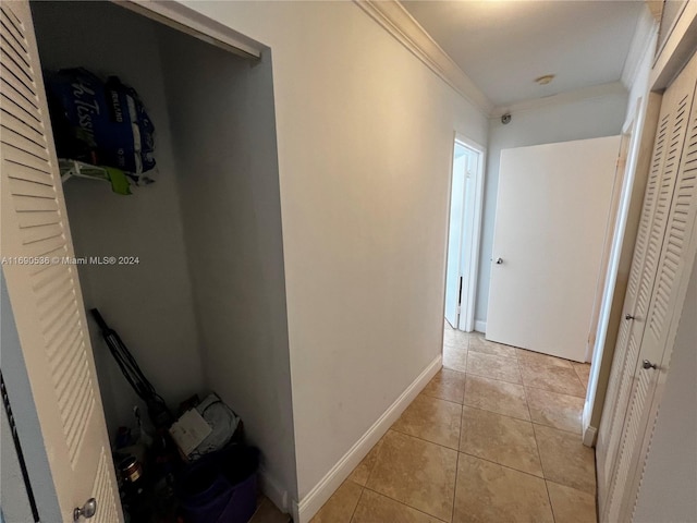 hall featuring light tile patterned floors and crown molding