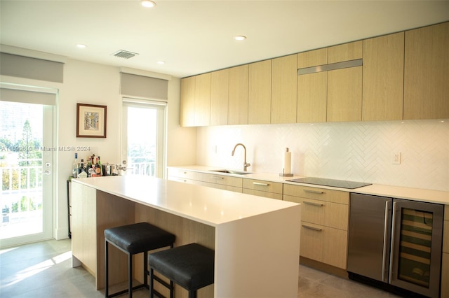 kitchen featuring wine cooler, a kitchen island, sink, and a healthy amount of sunlight