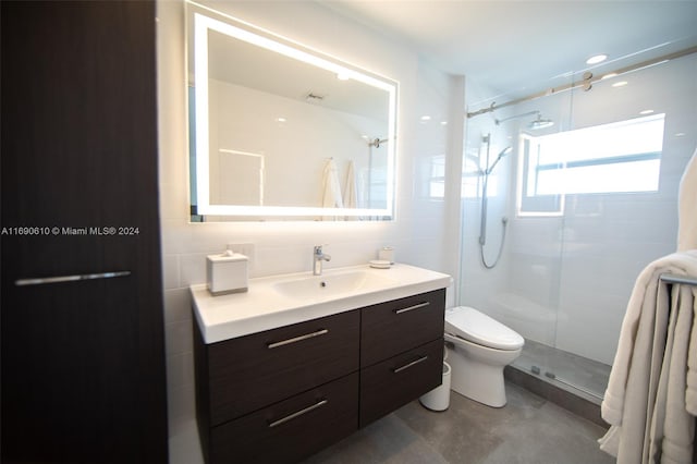 bathroom with a shower with door, vanity, toilet, and tile walls