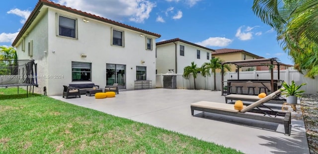 rear view of house with a patio area, a pergola, a lawn, and a trampoline