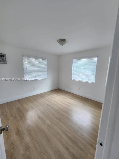 spare room featuring an AC wall unit and light hardwood / wood-style flooring