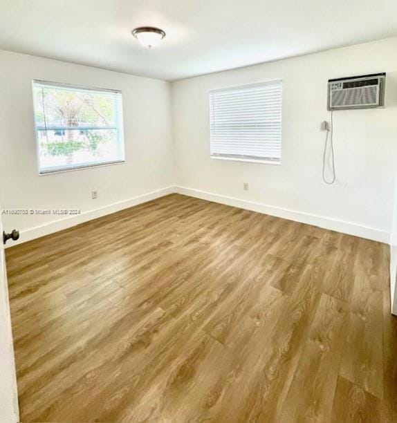 unfurnished room featuring hardwood / wood-style floors and a wall mounted air conditioner