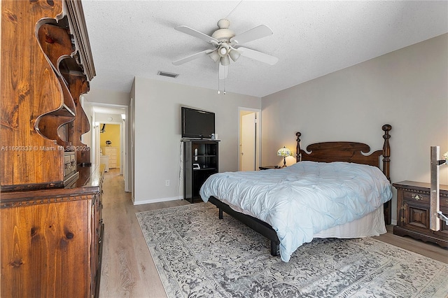 bedroom featuring ceiling fan, light hardwood / wood-style floors, and a textured ceiling