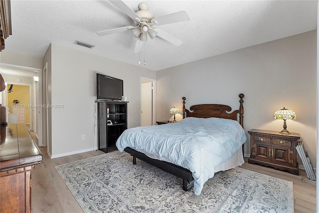 bedroom featuring ceiling fan, a textured ceiling, and light wood-type flooring