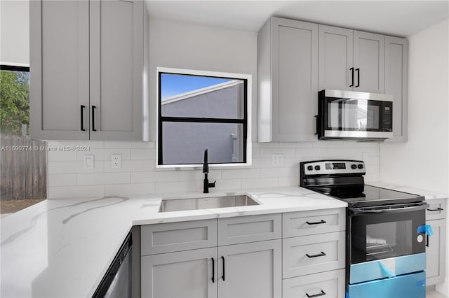 kitchen featuring a wealth of natural light, appliances with stainless steel finishes, gray cabinets, and sink