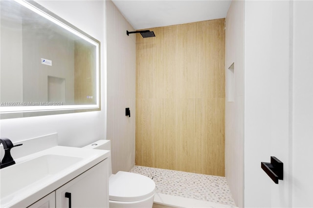 bathroom featuring toilet, vanity, and a tile shower