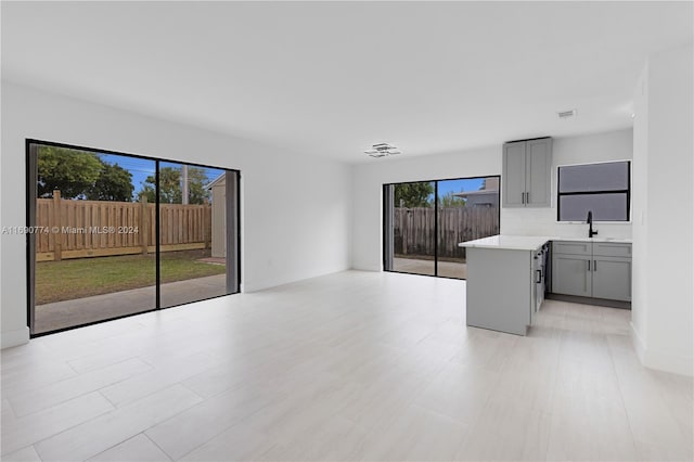 unfurnished living room featuring a wealth of natural light and sink