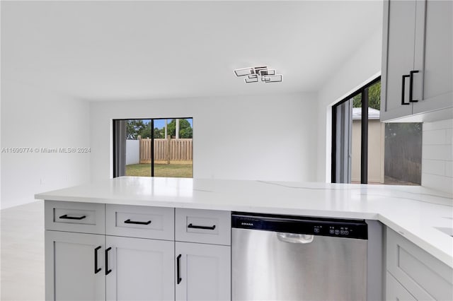 kitchen featuring light stone countertops, backsplash, and dishwasher