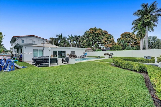 back of house with a fenced in pool, a yard, a patio, and an outdoor hangout area