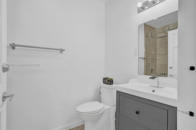 bathroom featuring a tile shower, vanity, and toilet